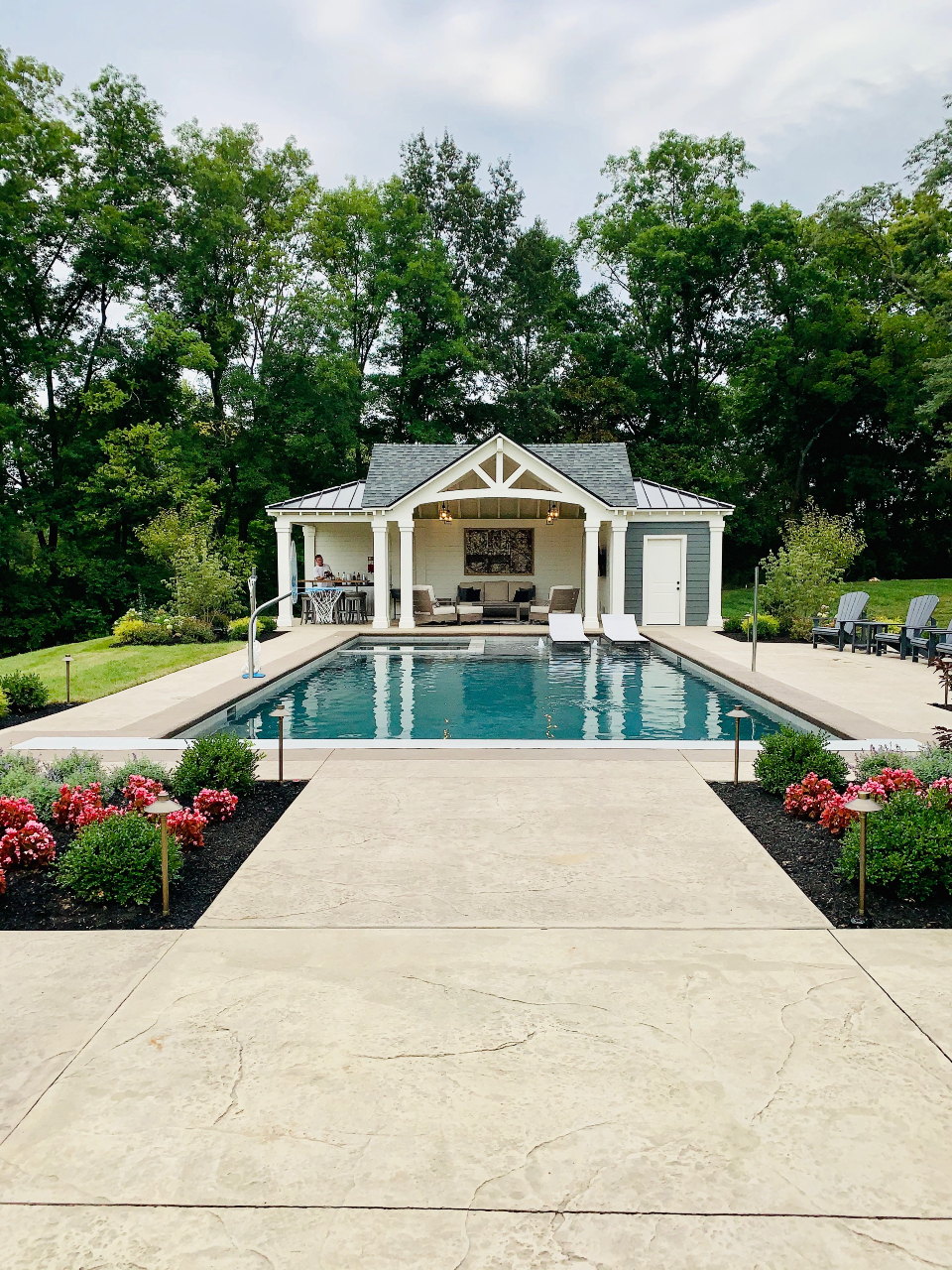 A pool house behind an in-ground pool