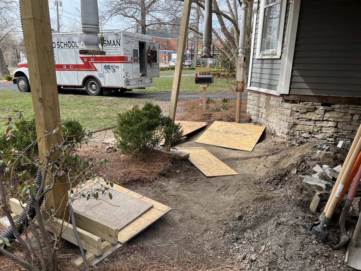 A truck next to a house with pieces of wood in the yard