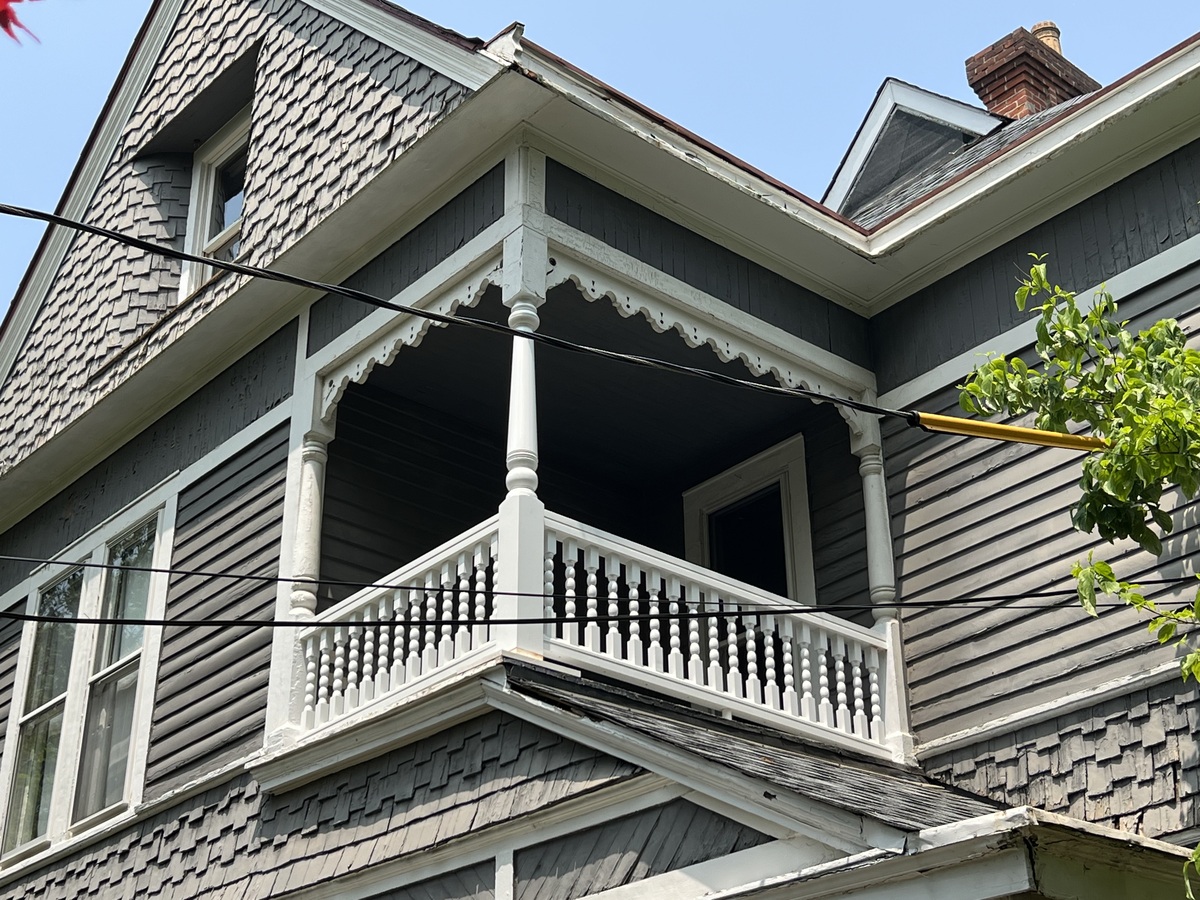 A gray and white Victorian home balcony