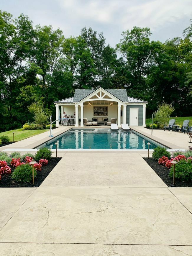 A pool house behind a swimming pool