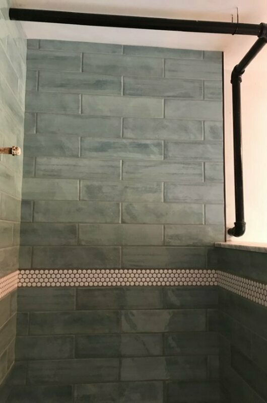shower with blue and white tile and piping